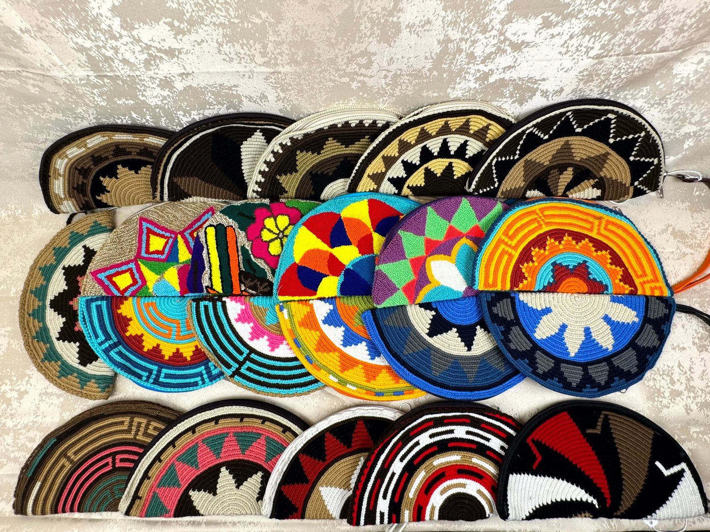 Collection of colorful woven hats with geometric patterns on a textured surface.