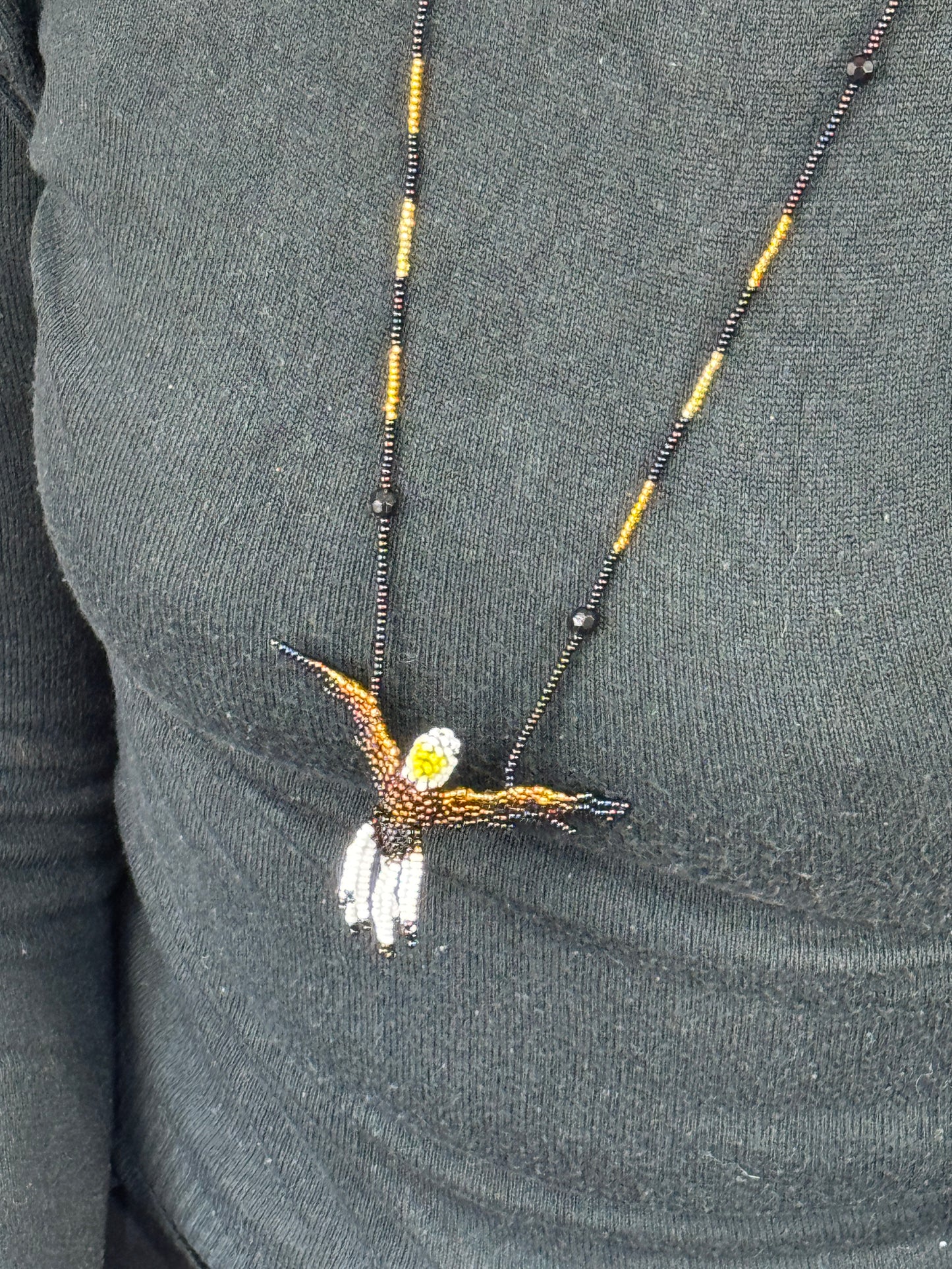 Detalle del tejido artesanal en collar pájaro aguila hecho a mano.