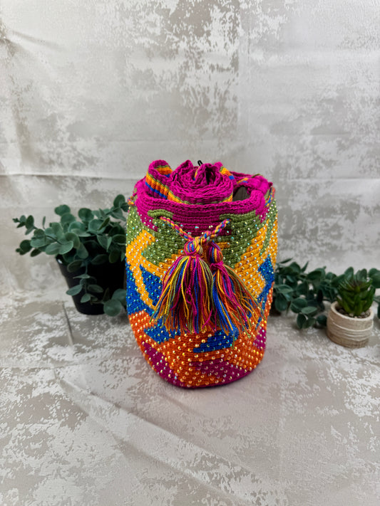 Vista frontal de mochila Wayuu mediana con piedras brillantes y patrón tradicional tejido a mano.