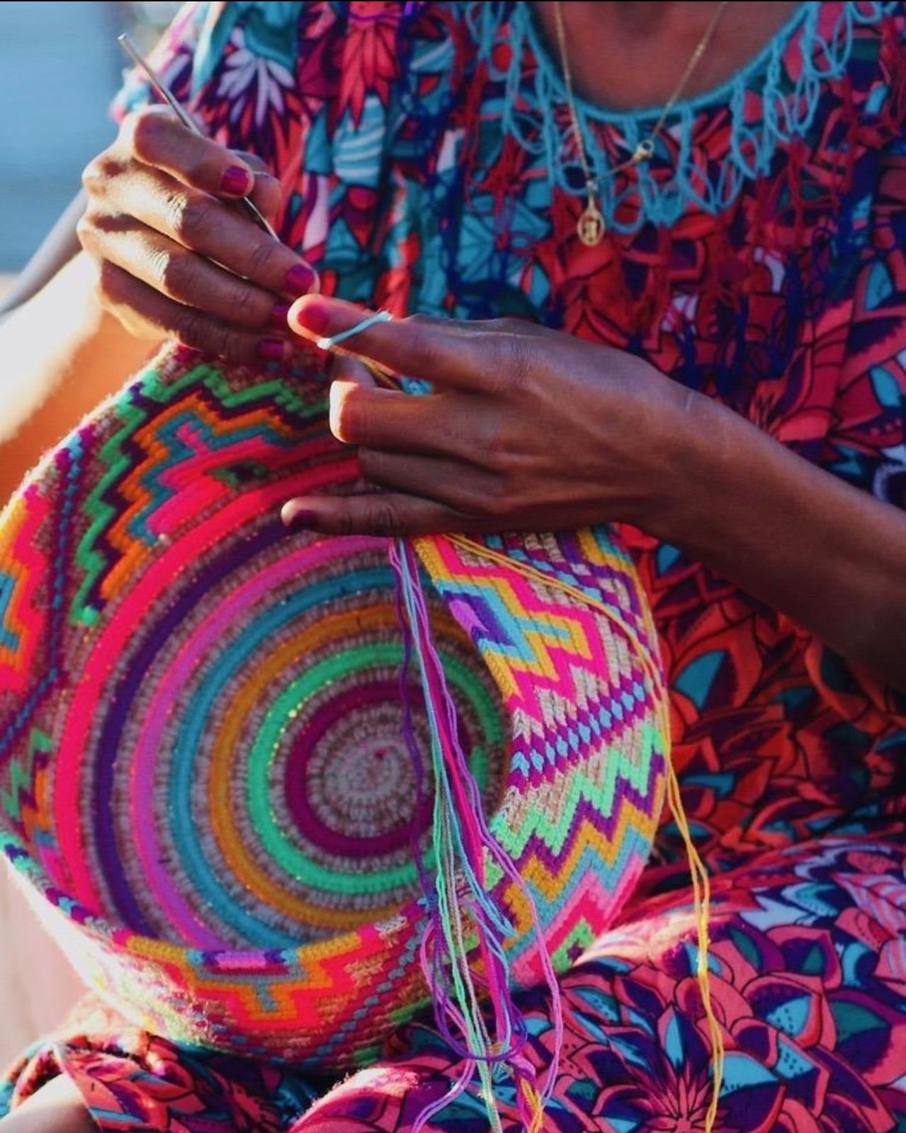 Person holding a colorful woven basket with intricate patterns