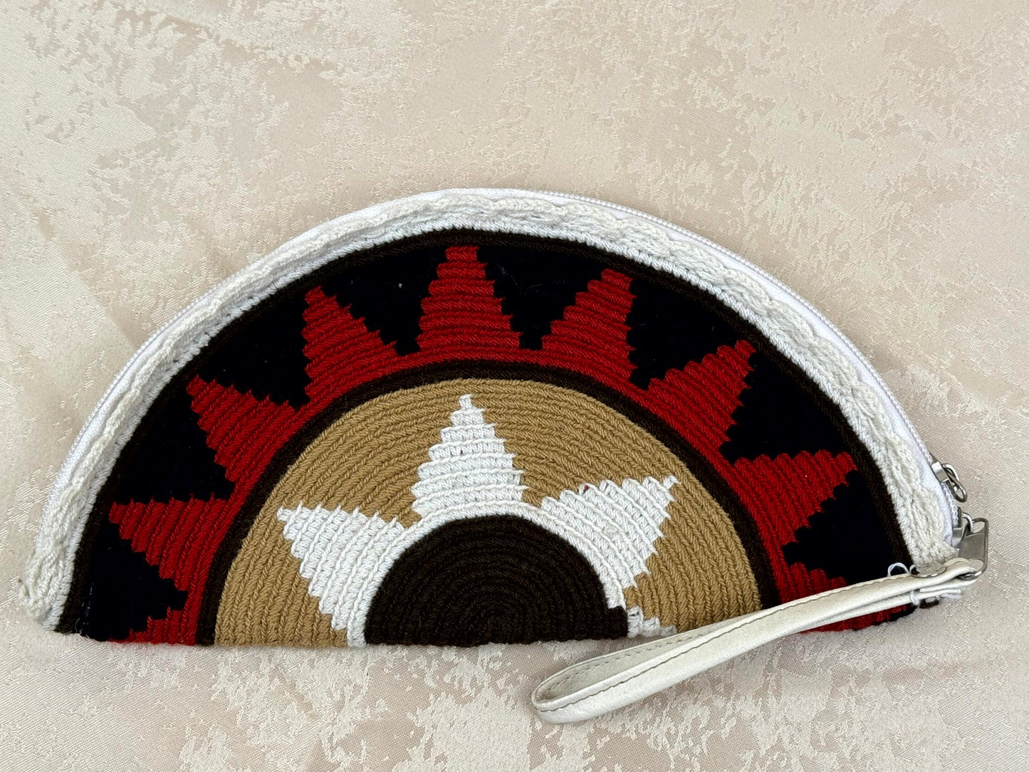 Half-circle pouch with geometric pattern on a textured beige background