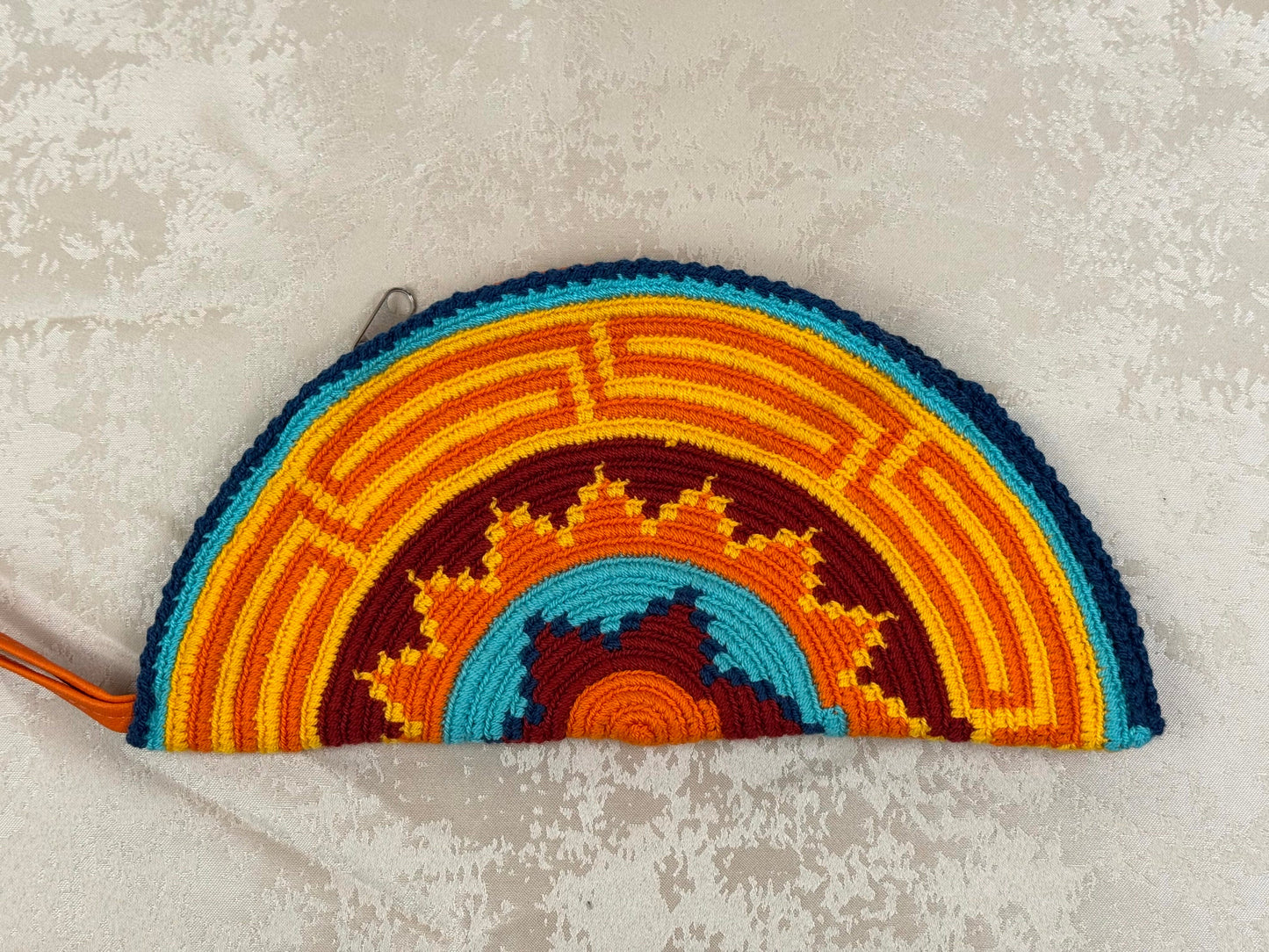 Colorful woven pouch with a geometric pattern on a textured surface