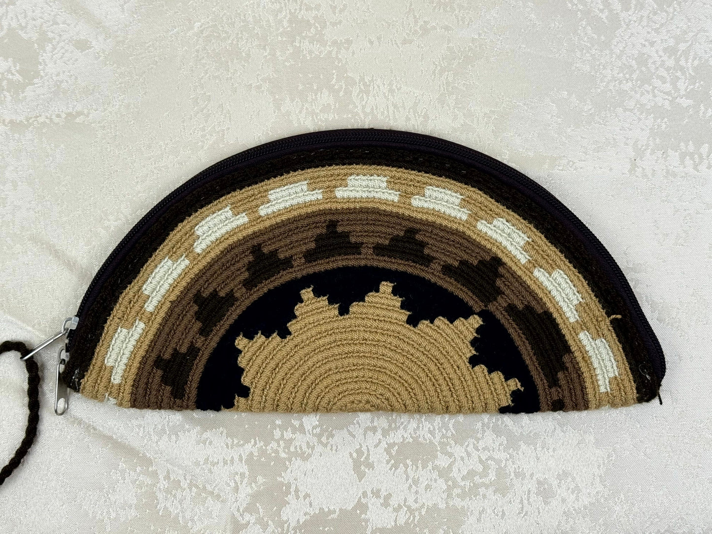 Half-circle woven pouch with geometric pattern on a textured white background