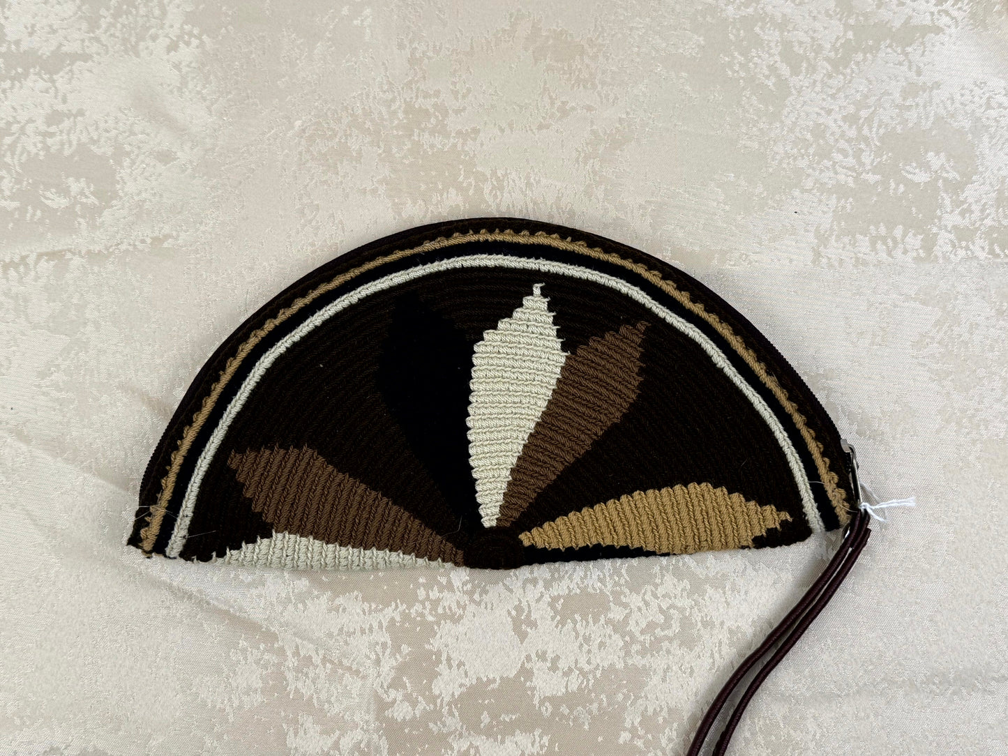 Decorative purse with black, brown, and beige pattern on a textured light gray background