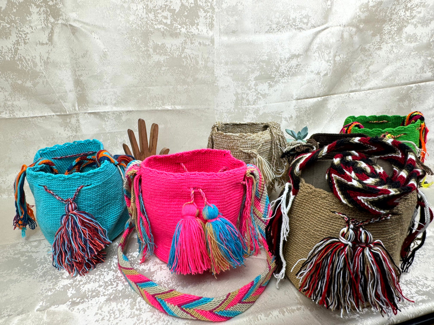 Colorful woven bags with tassels on a textured surface