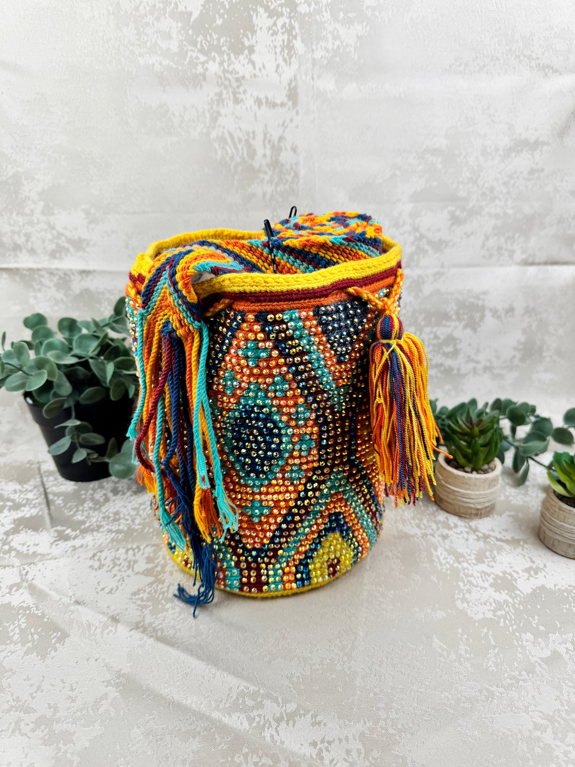 Vista frontal de mochila Wayuu mediana con piedras brillantes y diseño tradicional tejido a mano.