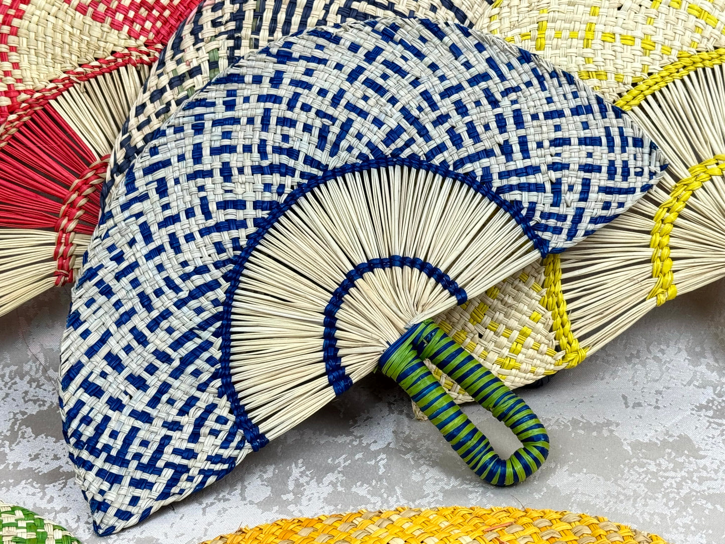 Abanico artesanal de iraca tejido a mano por artesanas colombianas con fibra natural de palma.