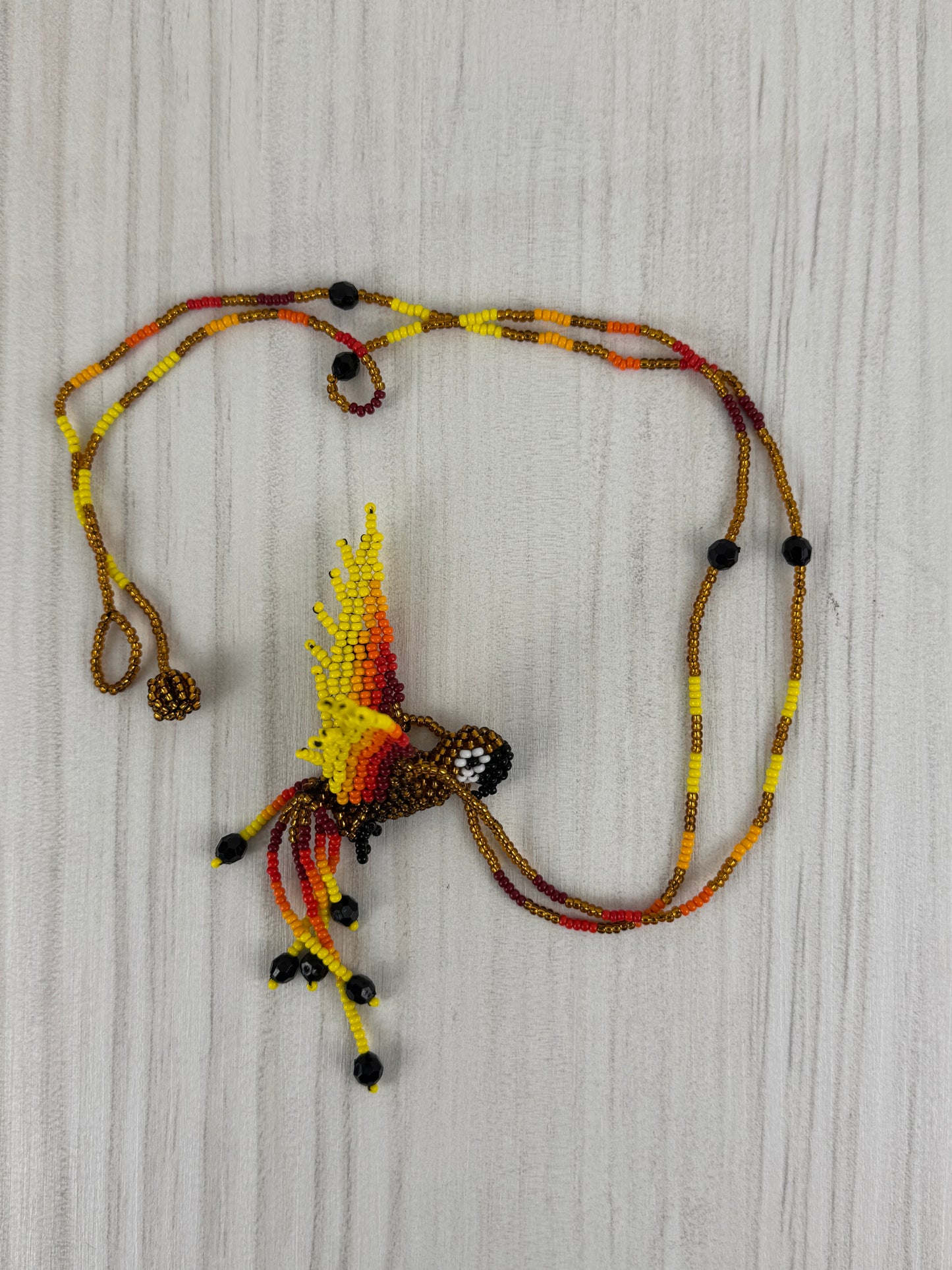 Collar pájaro lloro dorado tejido a mano edición limitada elaborado artesanalmente por artesanos latinoamericanos.