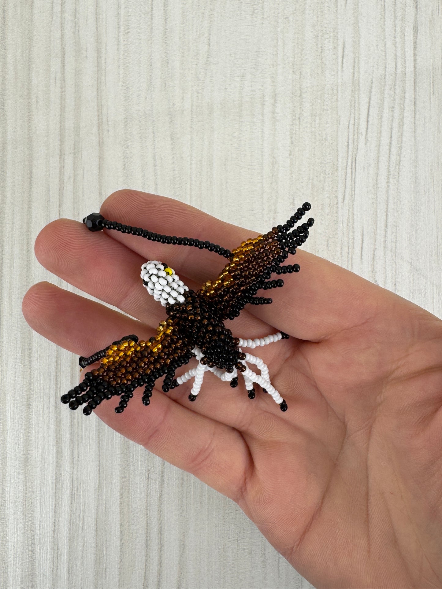 Detalle del pájaro aguila tejido a mano en collar artesanal edición limitada.