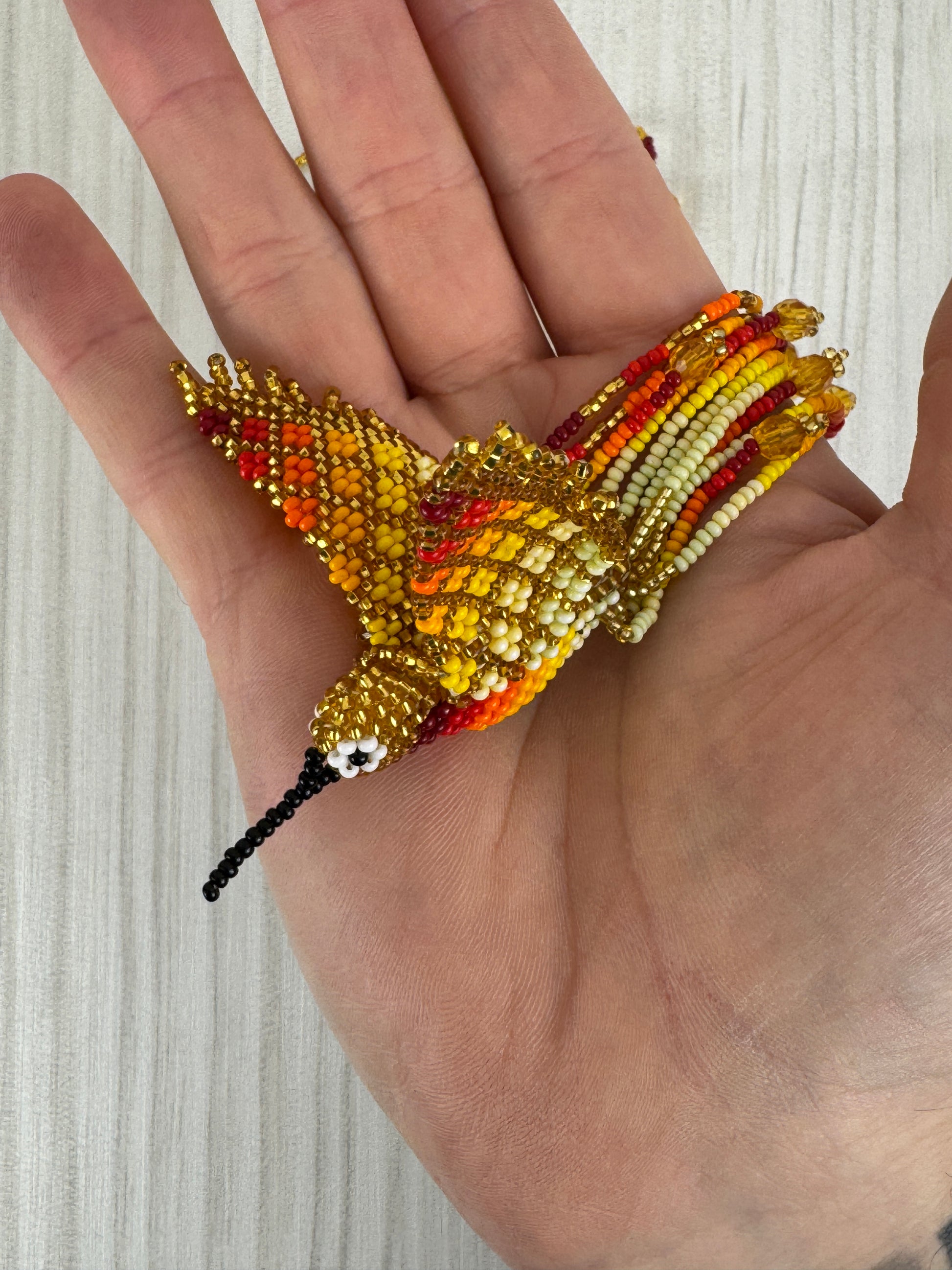 Detalle del pájaro colibri amarillo tejido a mano en collar artesanal edición limitada.