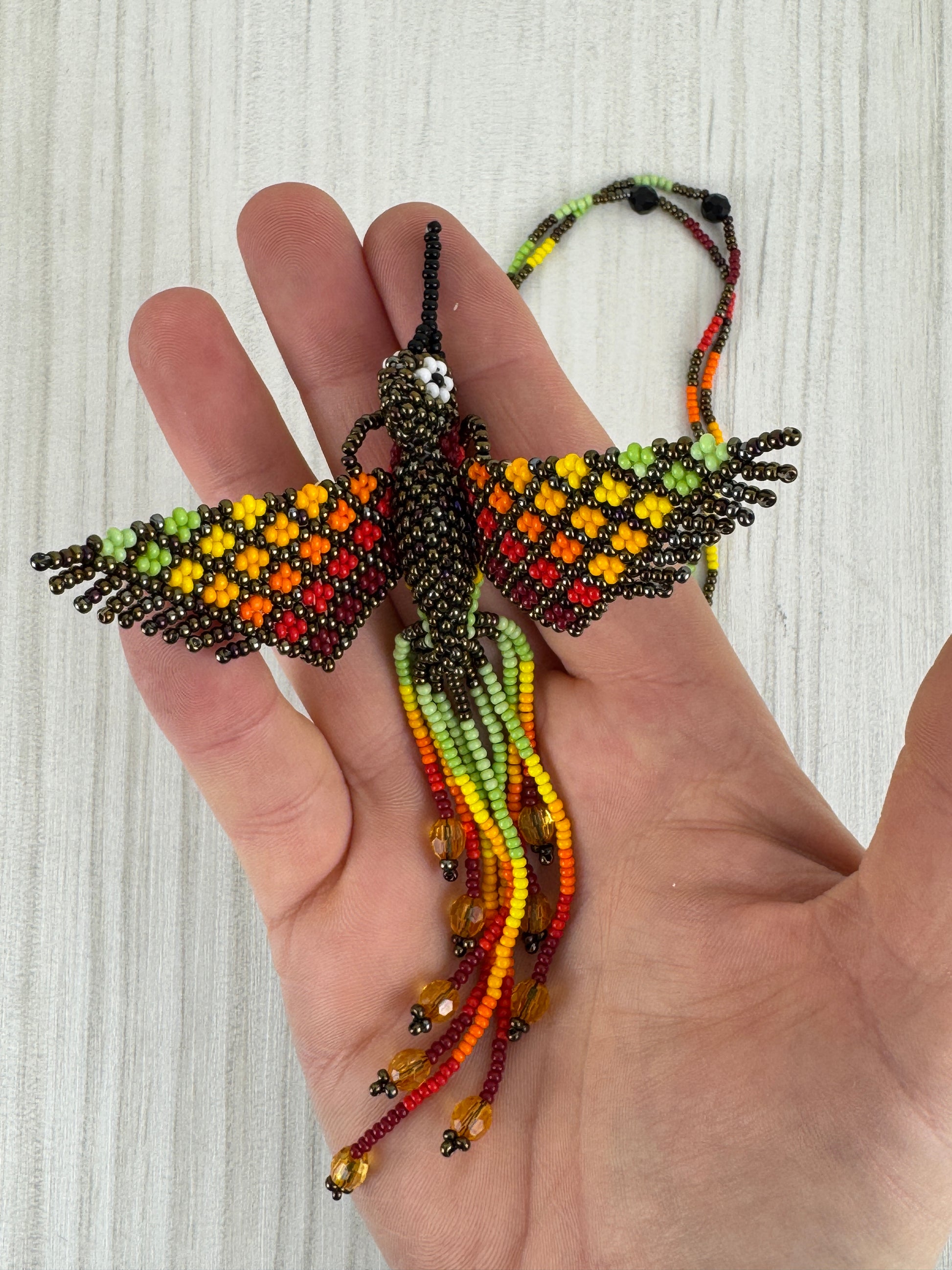 Detalle del pájaro tejido a mano en collar artesanal edición limitada.