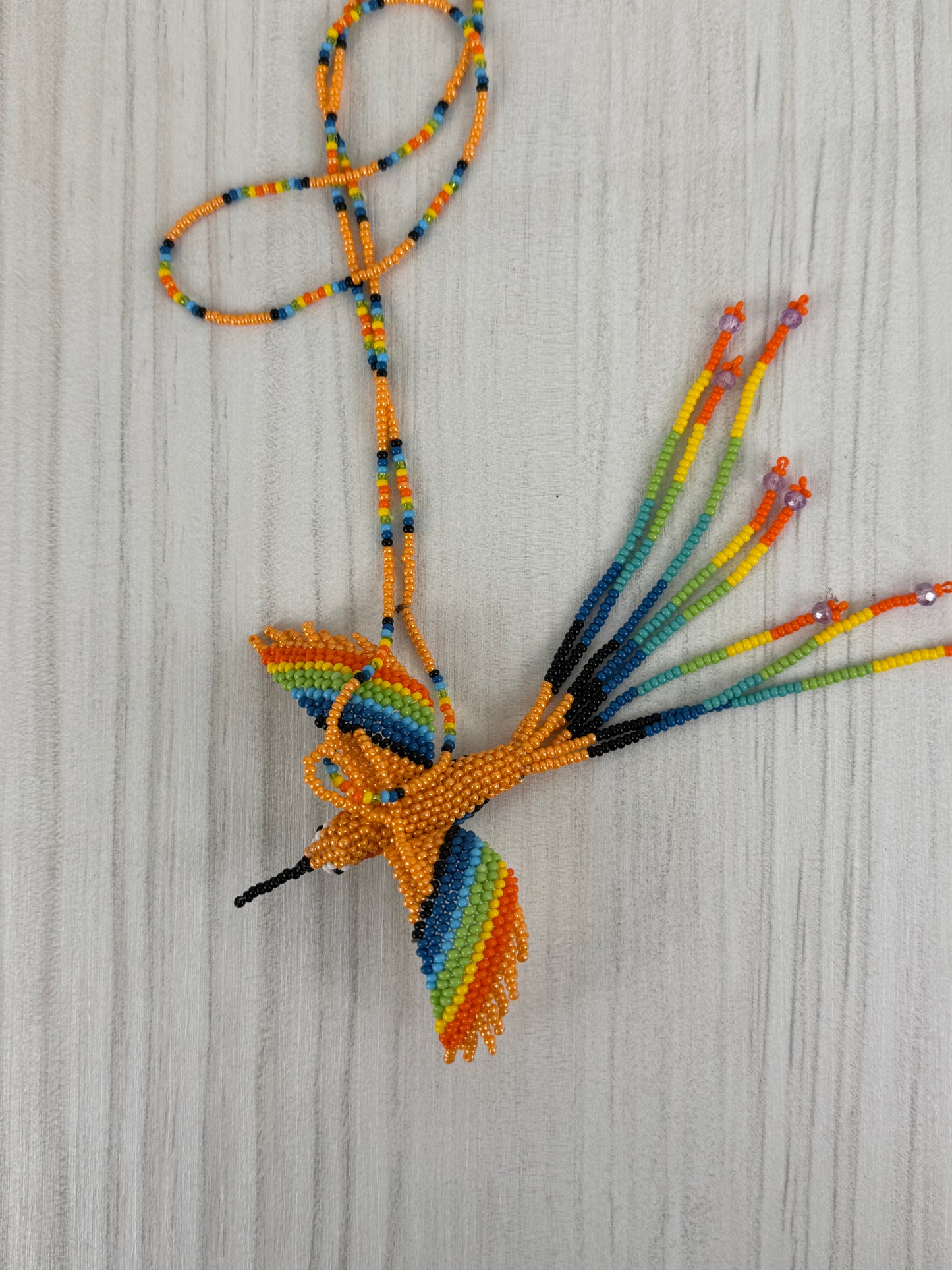 Detalle del pájaro colibri melocoton tejido a mano en collar artesanal edición limitada.