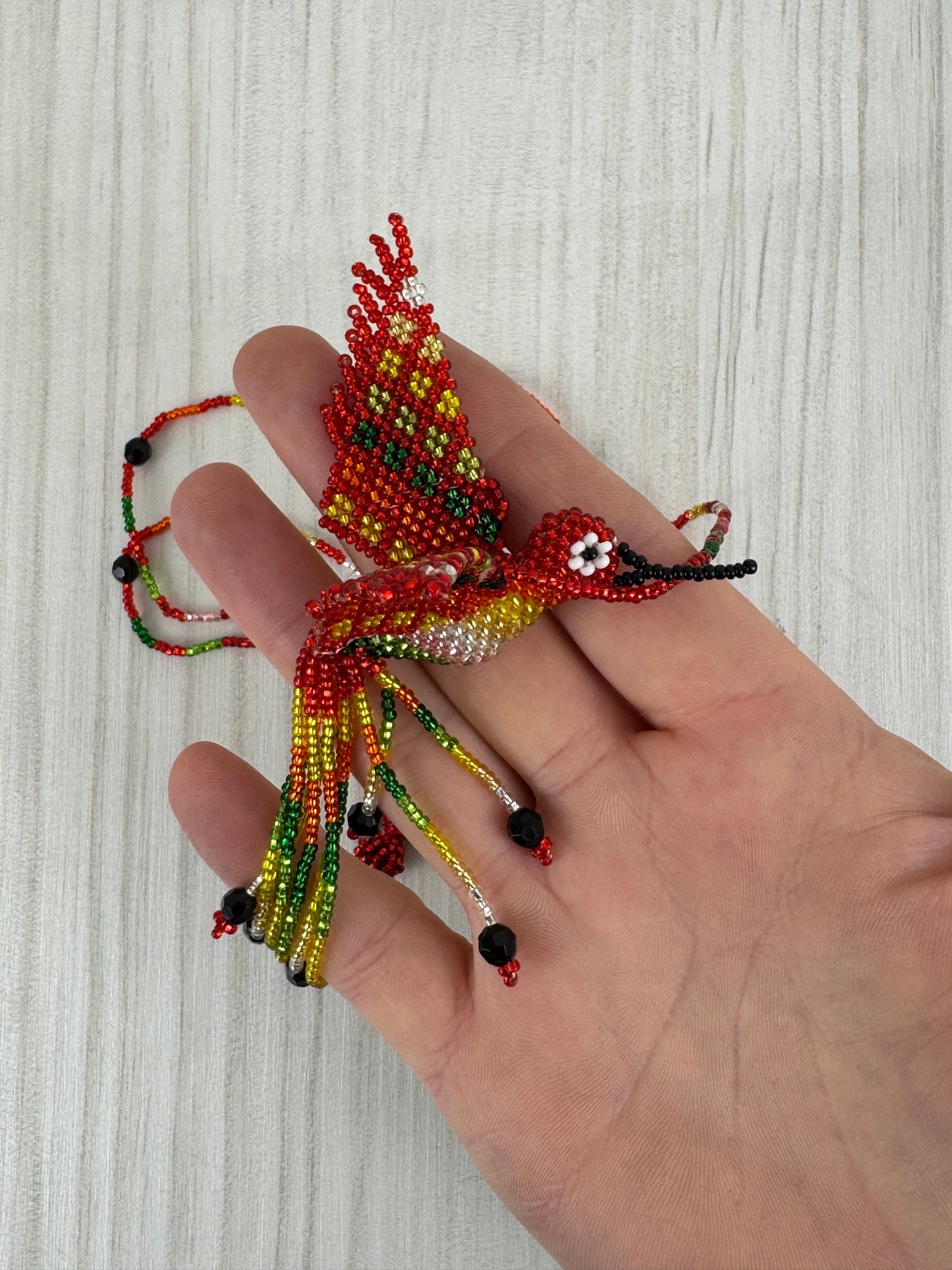 Detalle del pájaro colibri rojo tejido a mano en collar artesanal edición limitada.