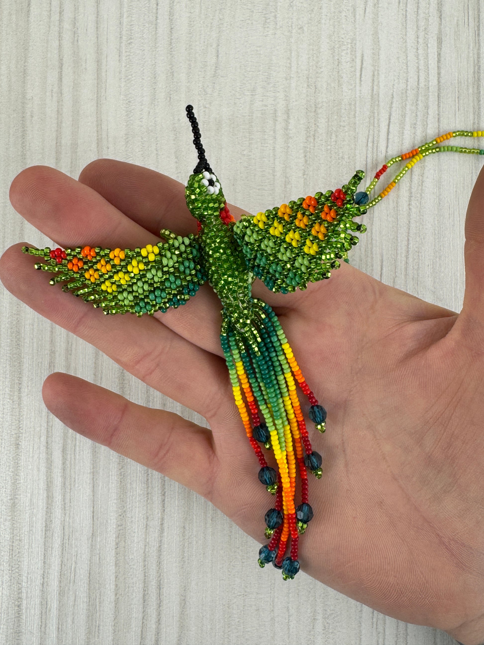 Detalle del pájaro tejido a mano en collar artesanal edición limitada.