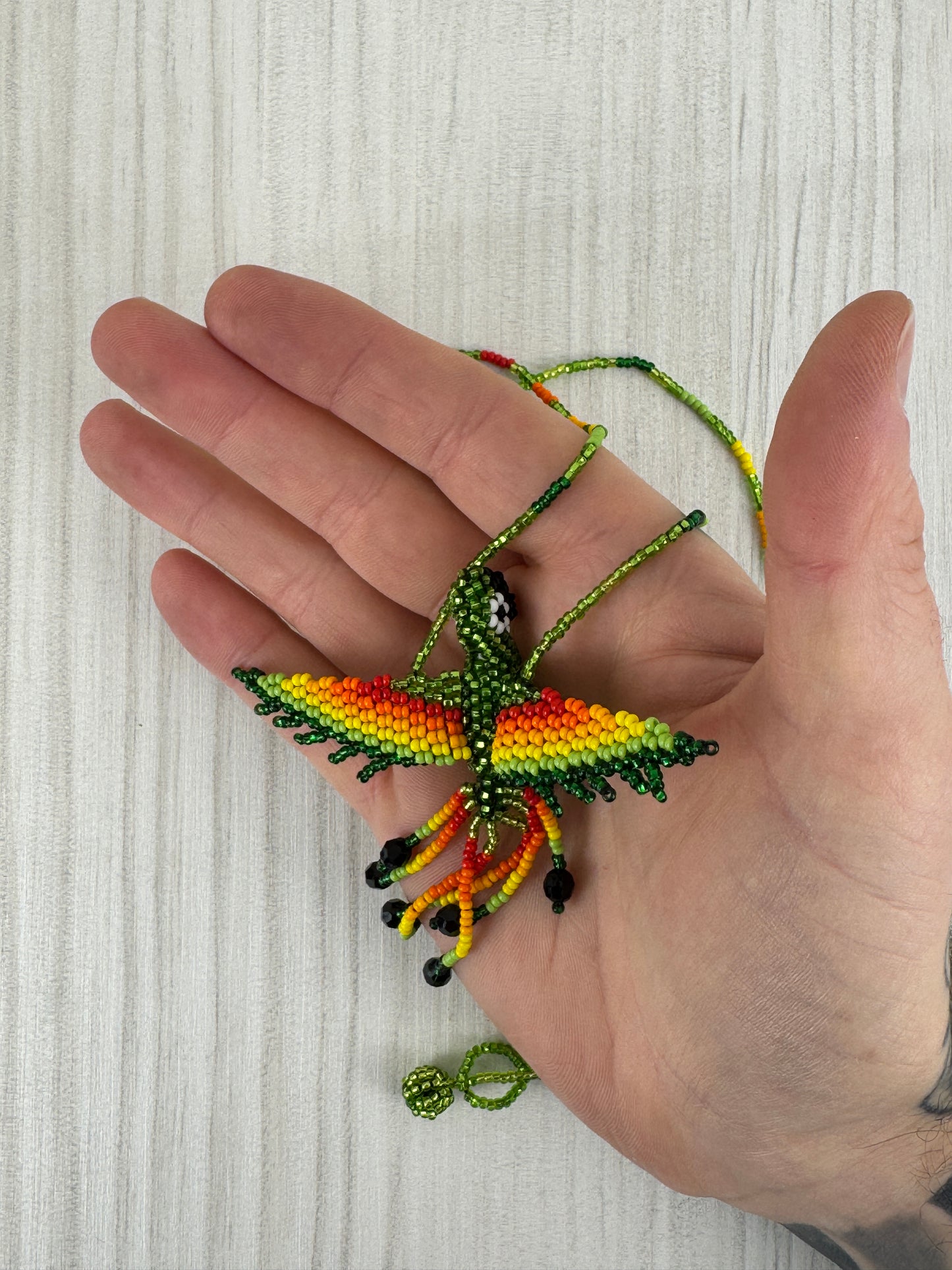 Detalle del pájaro tejido a mano en collar artesanal edición limitada.
