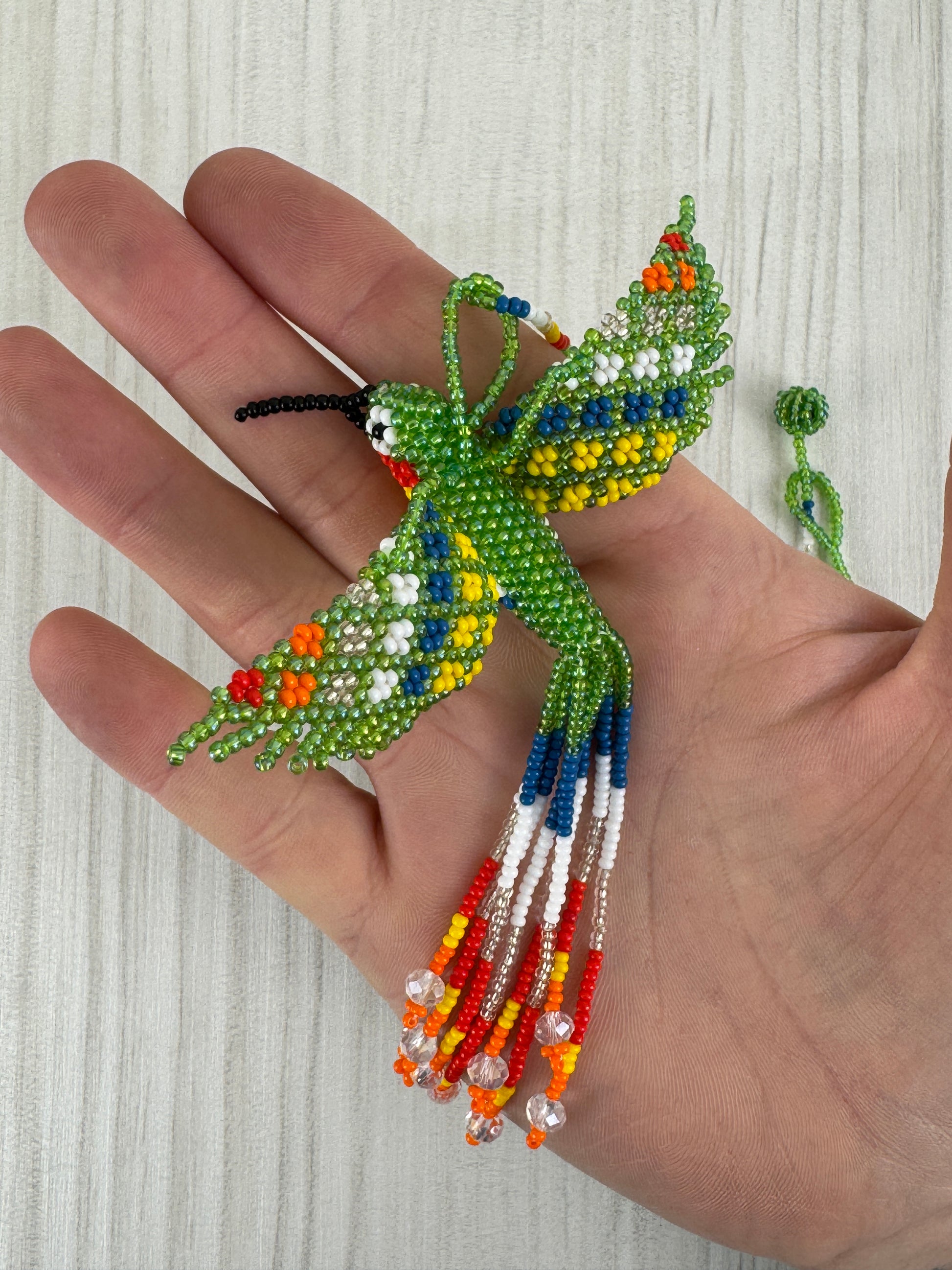 Detalle del pájaro colibri tejido a mano en collar artesanal edición limitada.
