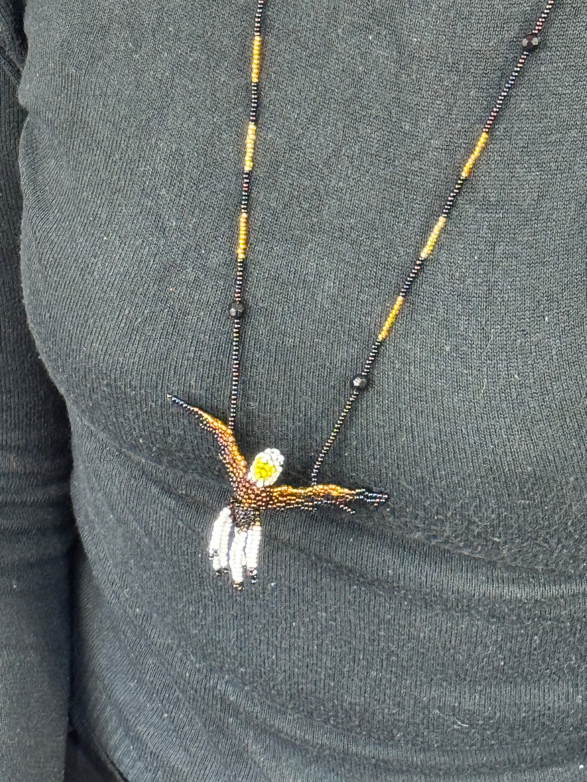 Detalle del tejido artesanal en collar pájaro aguila hecho a mano.