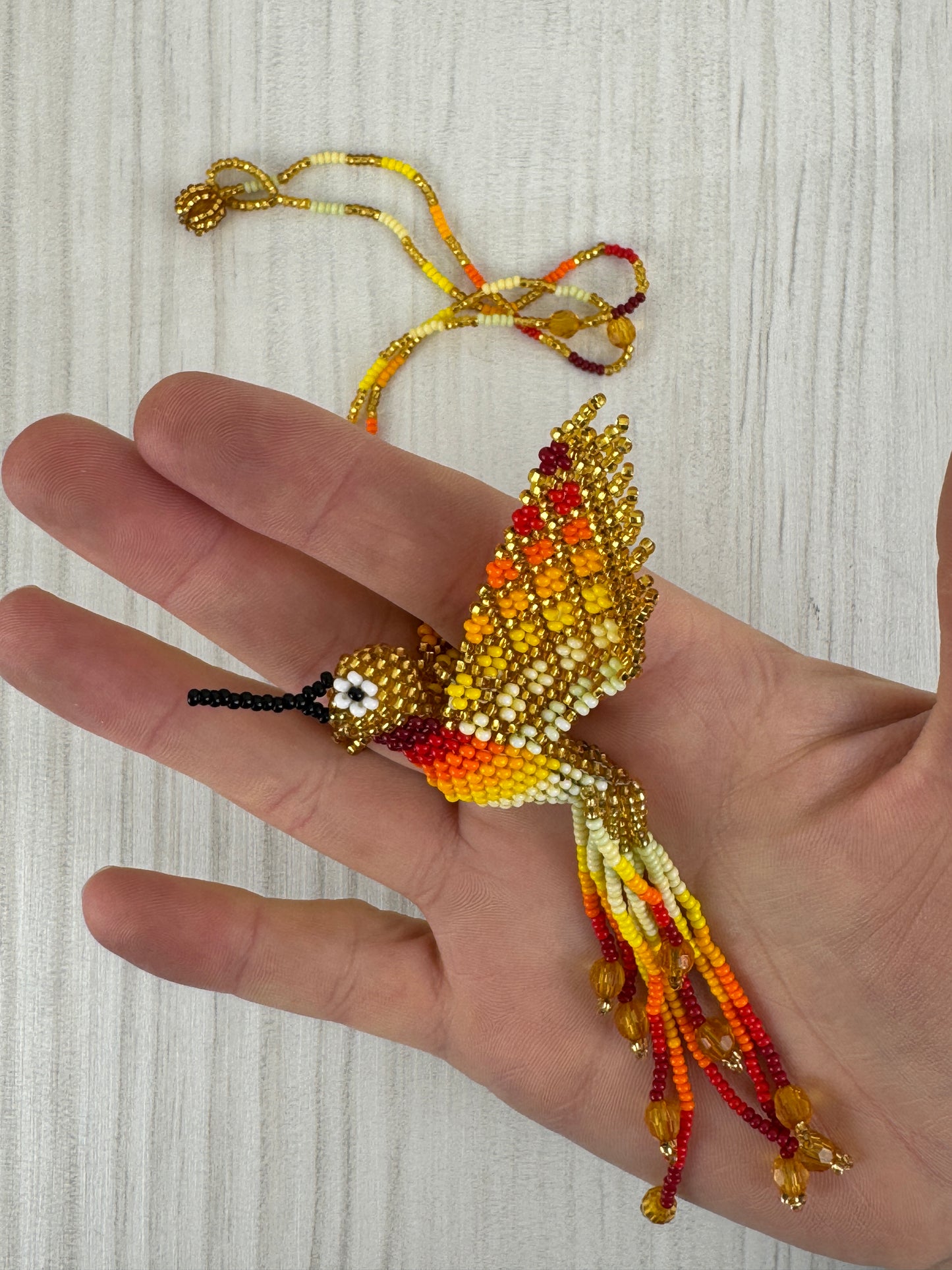Vista frontal de collar pájaro colibri amarillotejido a mano con diseño artesanal colorido.