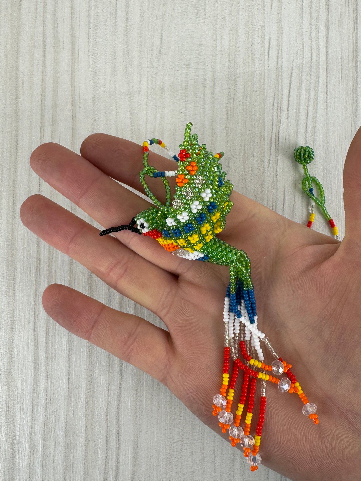 Vista frontal de collar pájaro colibri  tejido a mano con diseño artesanal colorido.