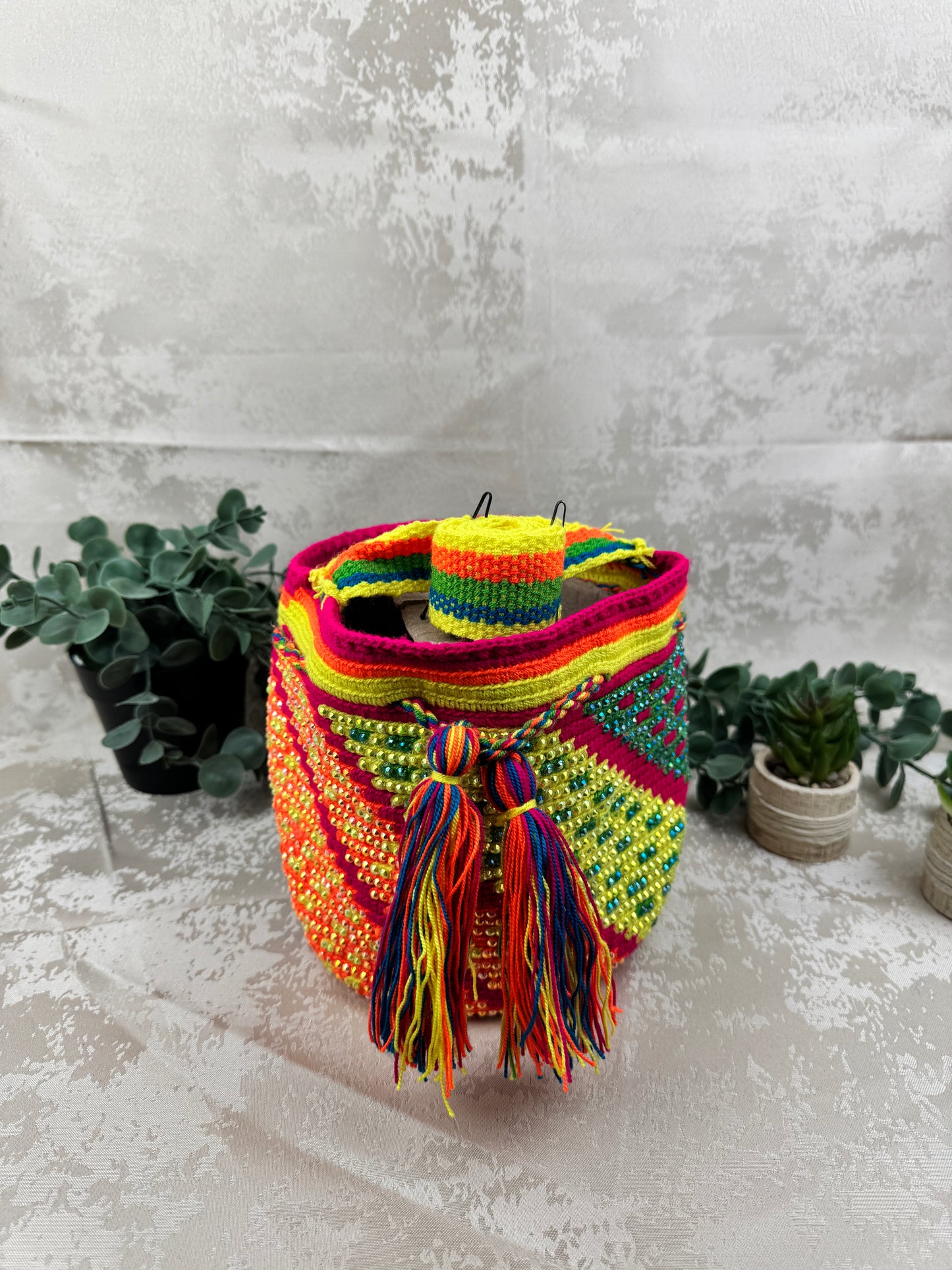 Vista frontal de mochila Wayuu mediana con piedras brillantes y diseño tradicional tejido a mano