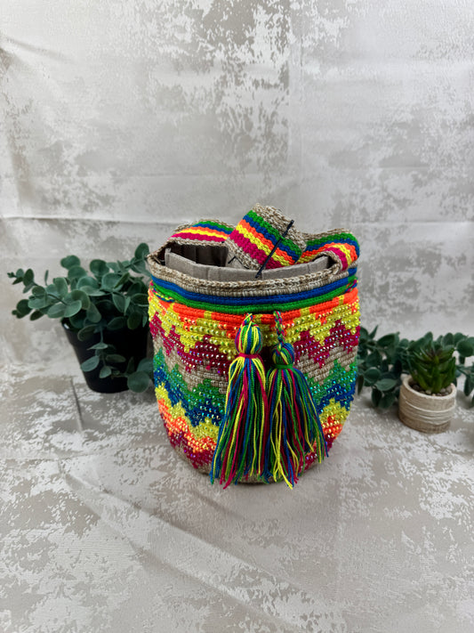 Vista frontal de mochila Wayuu mediana con piedras brillantes y diseño tradicional tejido a mano.