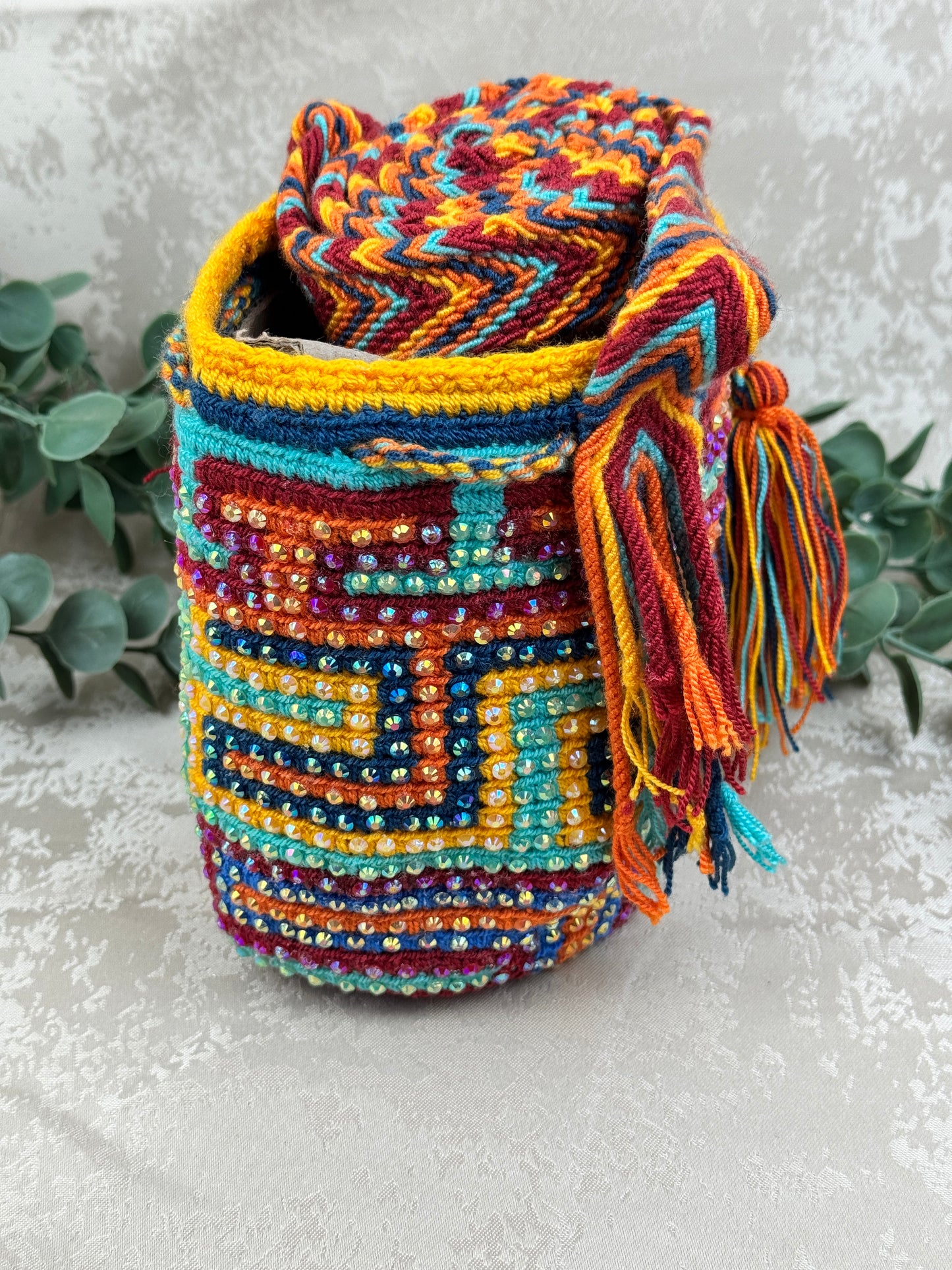 Vista frontal de mochila Wayuu Susuchón edición brillante 0 con piedras decorativas y tejido artesanal.