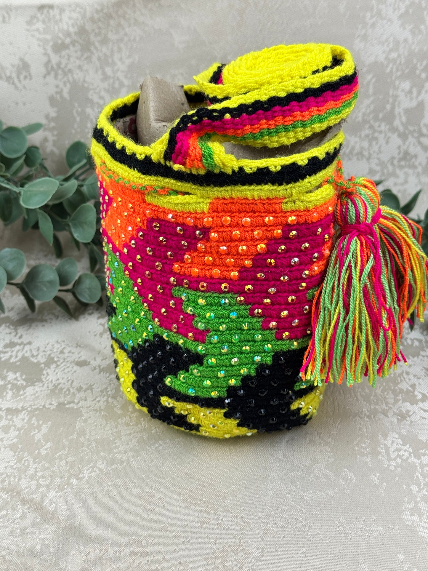 Vista frontal de mochila Wayuu Susuchón edición brillante 1 con piedras decorativas y tejido artesanal.
